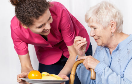 images of the ederly woman eating assisted by the aide